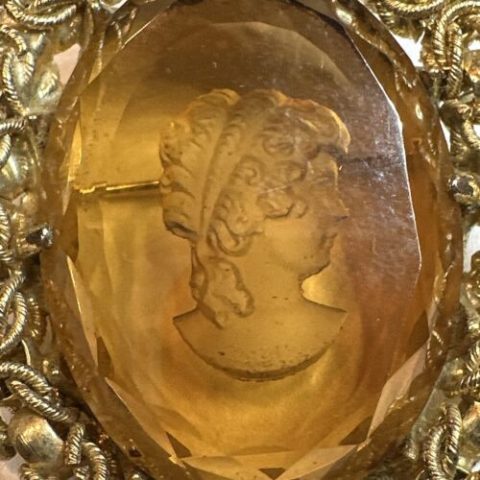 An amber cameo brooch depicting a side view portrait of a woman's face